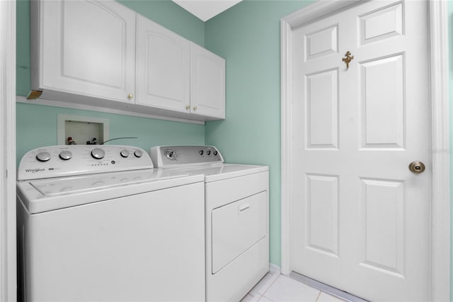 clothes washing area with cabinets, light tile patterned floors, and washing machine and clothes dryer