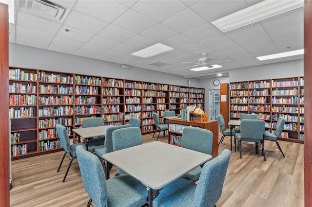 office space with light wood-type flooring, ceiling fan, and a drop ceiling