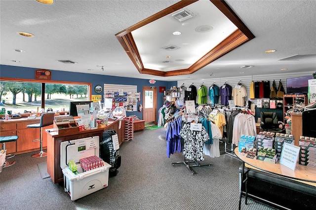 miscellaneous room featuring a textured ceiling, carpet floors, and a tray ceiling