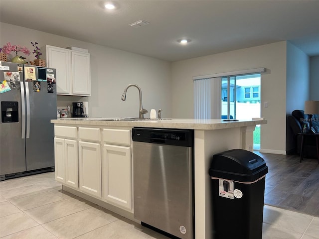 kitchen with white cabinets, appliances with stainless steel finishes, a kitchen island with sink, and sink