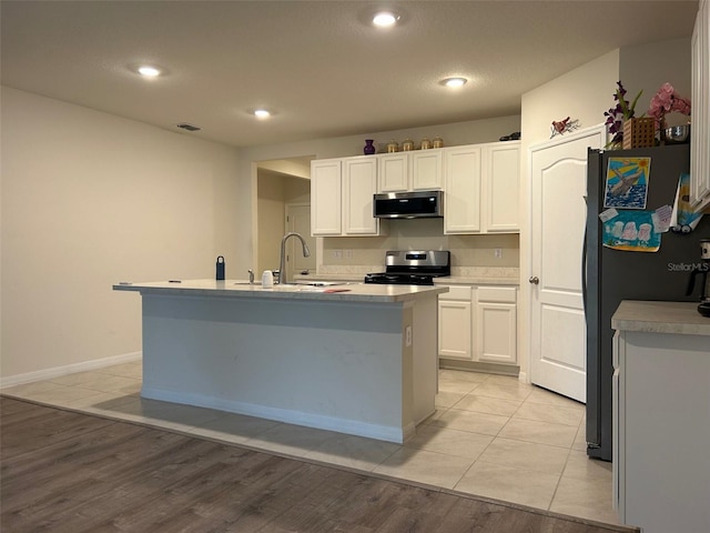 kitchen featuring sink, light tile patterned floors, a kitchen island with sink, white cabinets, and appliances with stainless steel finishes