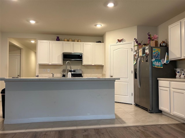 kitchen with a kitchen island with sink, white cabinets, stainless steel appliances, and light wood-type flooring