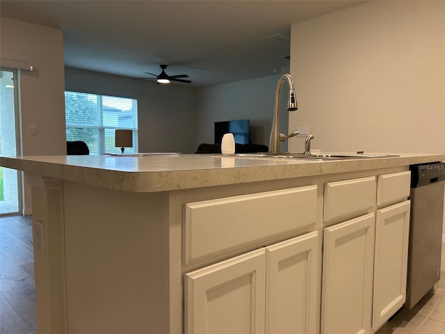 kitchen featuring ceiling fan, sink, white cabinets, stainless steel dishwasher, and light tile patterned flooring