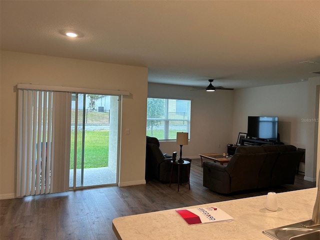 living room featuring dark hardwood / wood-style floors, ceiling fan, and a healthy amount of sunlight