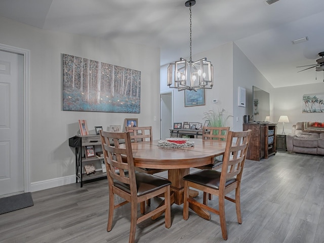 dining room featuring lofted ceiling, wood-type flooring, and ceiling fan with notable chandelier