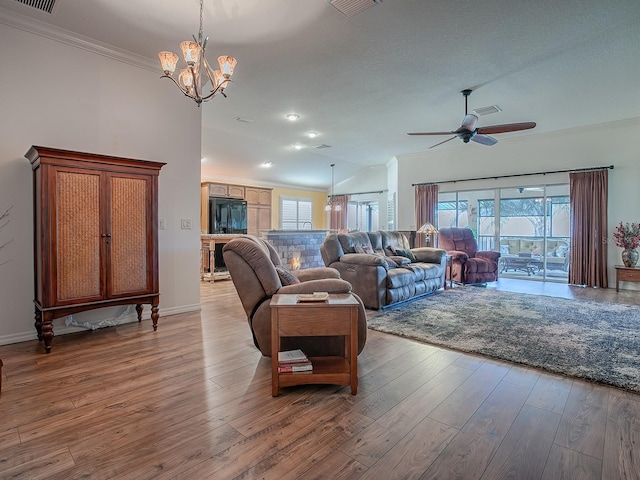 living room with ceiling fan with notable chandelier, plenty of natural light, light hardwood / wood-style floors, and a textured ceiling