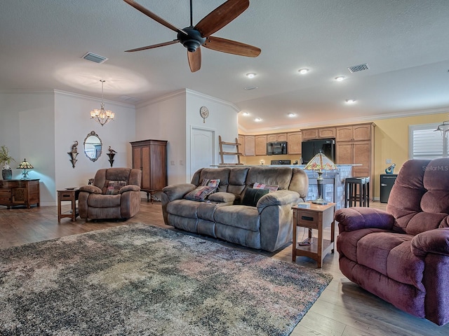 living room featuring crown molding, ceiling fan with notable chandelier, light hardwood / wood-style floors, and a textured ceiling