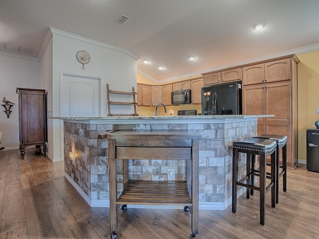 kitchen with crown molding, lofted ceiling, a breakfast bar area, and black appliances