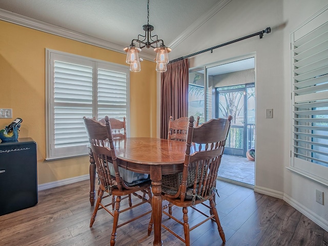 dining area with a notable chandelier, crown molding, vaulted ceiling, and hardwood / wood-style flooring