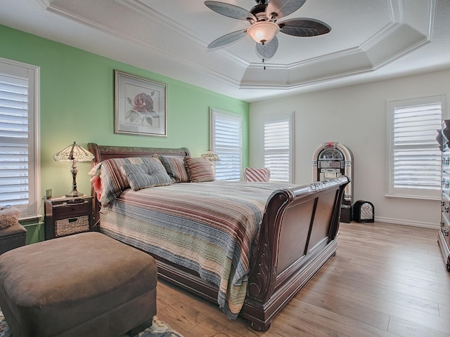 bedroom with crown molding, ceiling fan, a tray ceiling, and light wood-type flooring