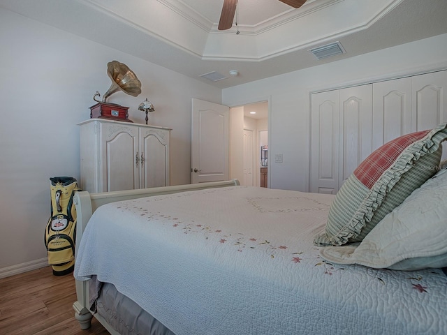 bedroom featuring hardwood / wood-style flooring, ceiling fan, crown molding, and a closet