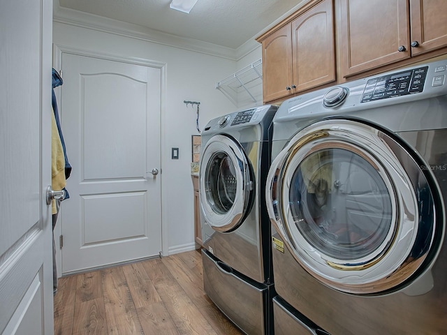 laundry room with cabinets, crown molding, separate washer and dryer, and light wood-type flooring