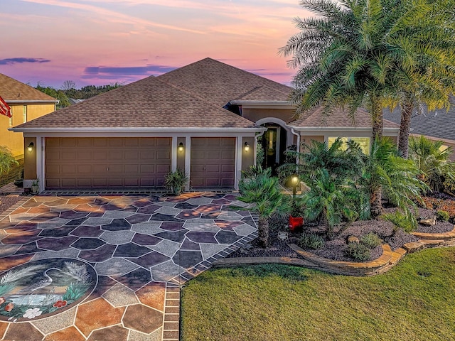 view of front facade featuring stucco siding, driveway, an attached garage, and a shingled roof