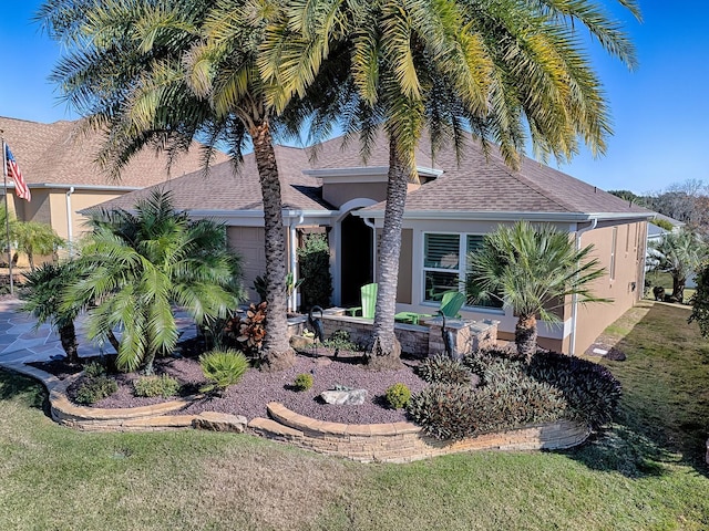 view of front of house with stucco siding, a garage, roof with shingles, and a front yard