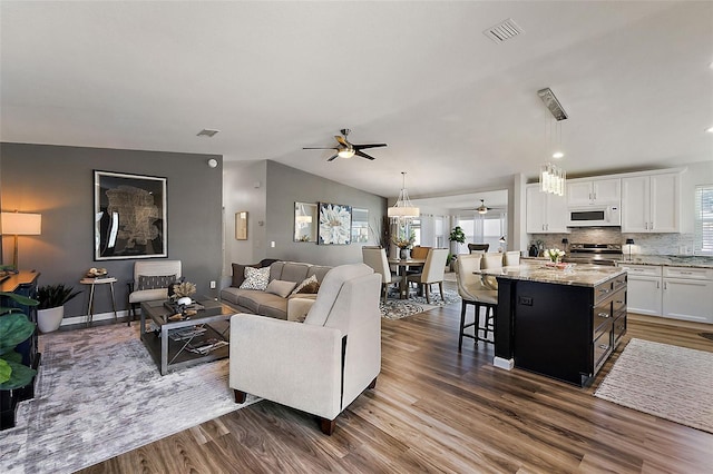 living room with ceiling fan, vaulted ceiling, and dark wood-type flooring