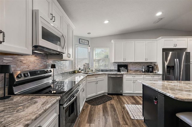 kitchen with sink, decorative light fixtures, white cabinets, vaulted ceiling, and appliances with stainless steel finishes