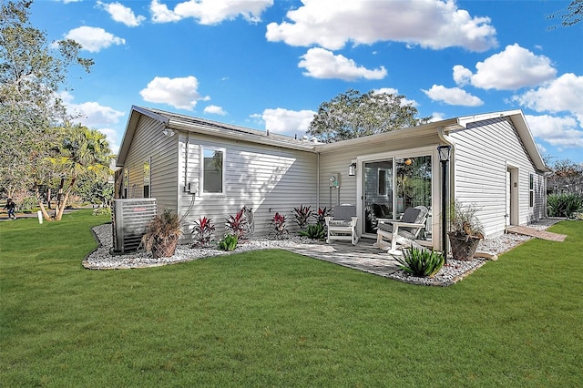 rear view of house with cooling unit, a patio, and a lawn