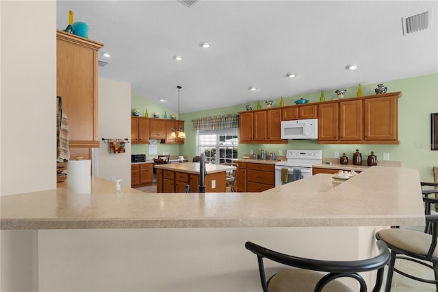 kitchen featuring white appliances, decorative light fixtures, a kitchen bar, and kitchen peninsula