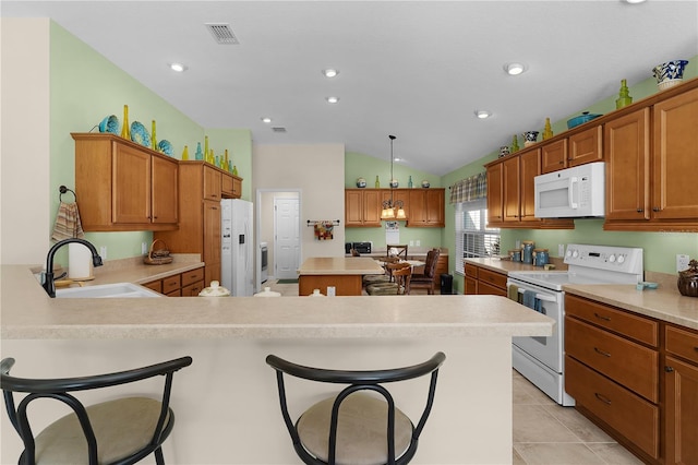 kitchen featuring white appliances, decorative light fixtures, a breakfast bar, lofted ceiling, and sink