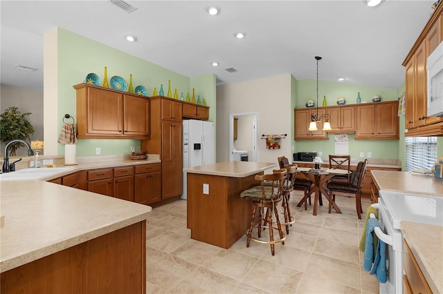 kitchen with sink, vaulted ceiling, white appliances, hanging light fixtures, and a kitchen island