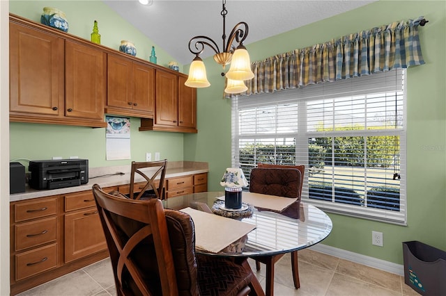 tiled dining room featuring vaulted ceiling and a chandelier