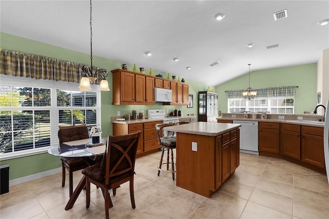 kitchen with white appliances, pendant lighting, a kitchen island, an inviting chandelier, and lofted ceiling