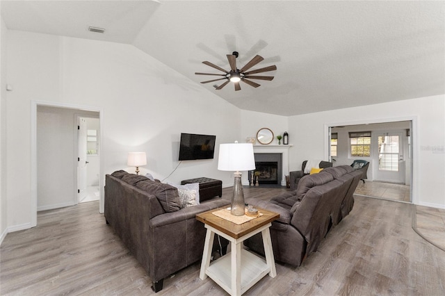 living room featuring ceiling fan, light hardwood / wood-style floors, and vaulted ceiling