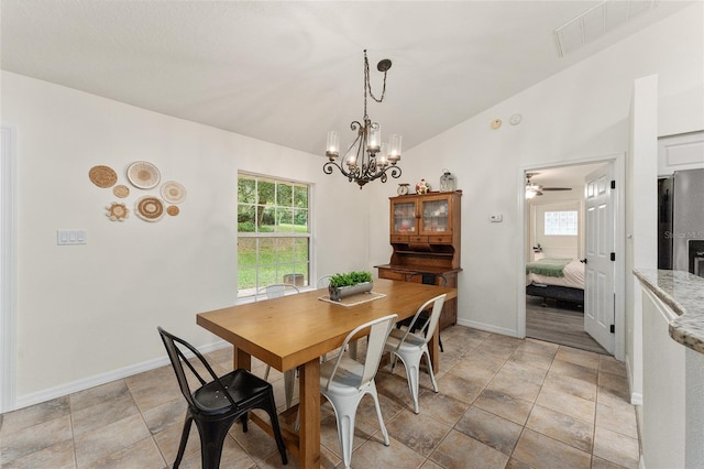 dining room featuring ceiling fan with notable chandelier and vaulted ceiling