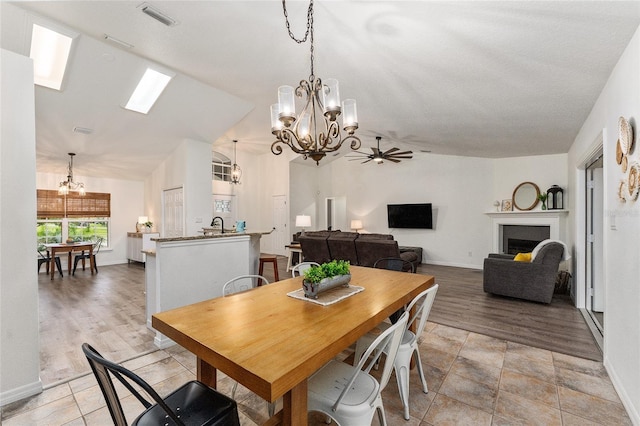 dining space featuring ceiling fan with notable chandelier and vaulted ceiling