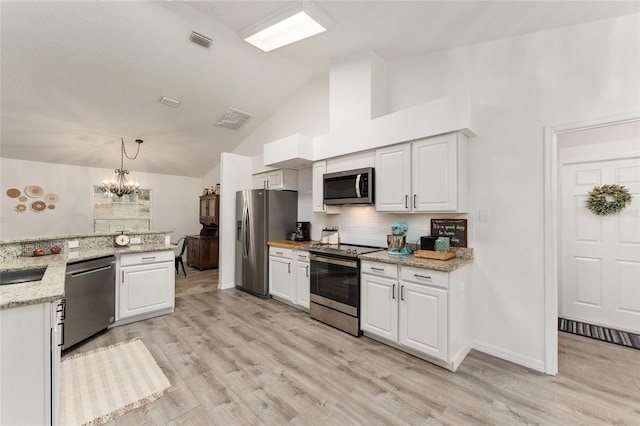 kitchen featuring light stone countertops, stainless steel appliances, tasteful backsplash, decorative light fixtures, and white cabinets