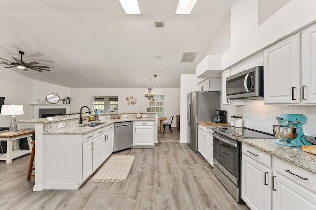 kitchen featuring white cabinetry, sink, decorative light fixtures, a breakfast bar area, and appliances with stainless steel finishes