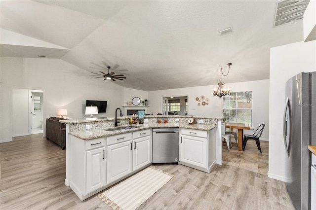 kitchen featuring sink, light stone counters, vaulted ceiling, white cabinets, and appliances with stainless steel finishes