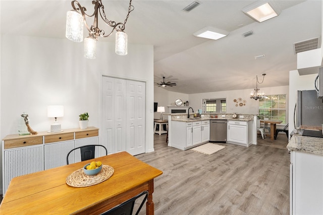 kitchen with kitchen peninsula, ceiling fan with notable chandelier, stainless steel appliances, pendant lighting, and white cabinets