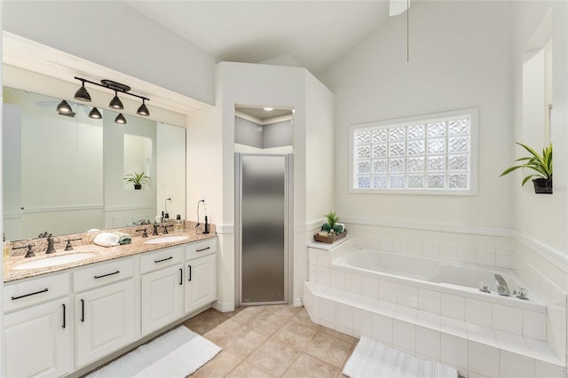 bathroom with tile patterned flooring, vanity, a relaxing tiled tub, and vaulted ceiling