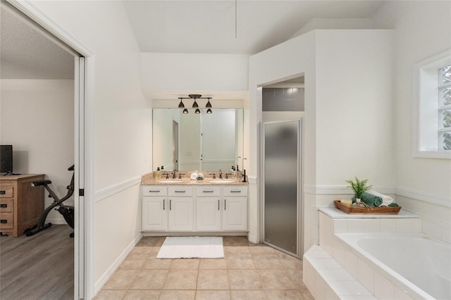 bathroom featuring tile patterned flooring, vanity, and a relaxing tiled tub