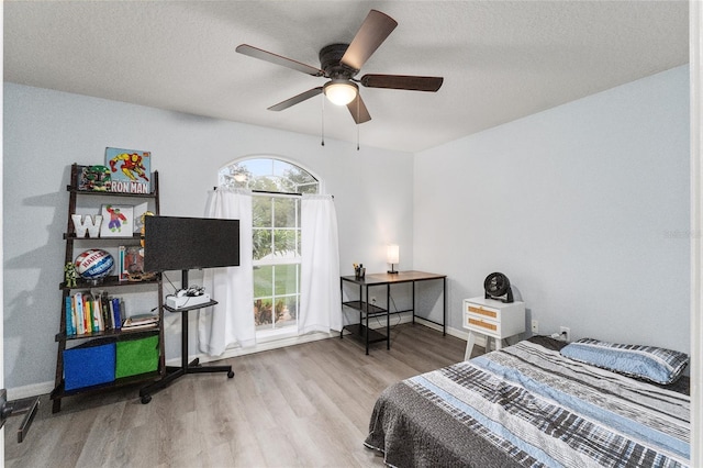 bedroom with ceiling fan, light hardwood / wood-style flooring, and a textured ceiling