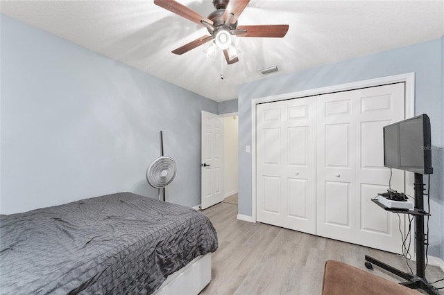 bedroom featuring ceiling fan, a closet, a textured ceiling, and light hardwood / wood-style flooring