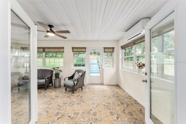 sunroom featuring a wall unit AC and ceiling fan