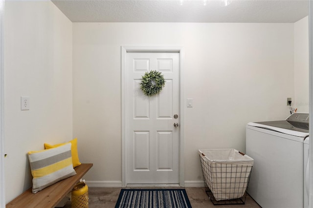 clothes washing area with hardwood / wood-style floors, a textured ceiling, and washer / dryer