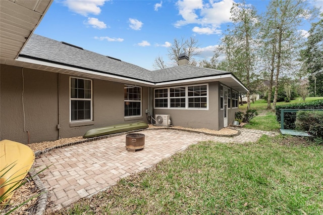 rear view of house with ac unit, a yard, a patio, and an outdoor fire pit