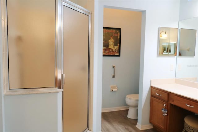 bathroom with toilet, vanity, a shower with shower door, and hardwood / wood-style flooring