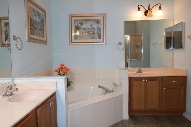 bathroom featuring tiled tub, hardwood / wood-style floors, and vanity