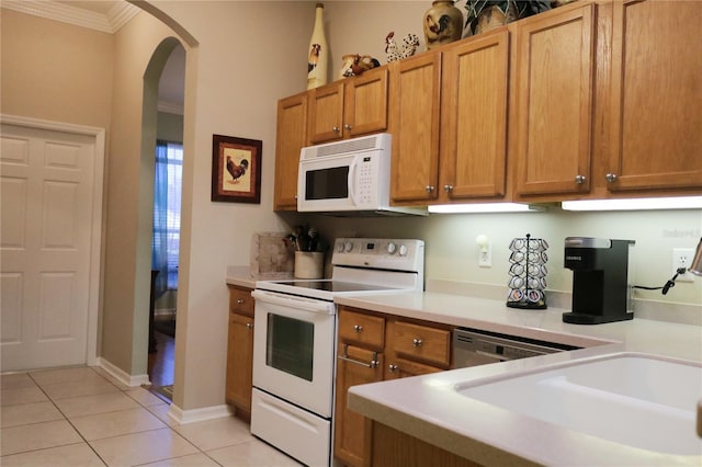 kitchen featuring sink, white appliances, crown molding, and light tile patterned flooring