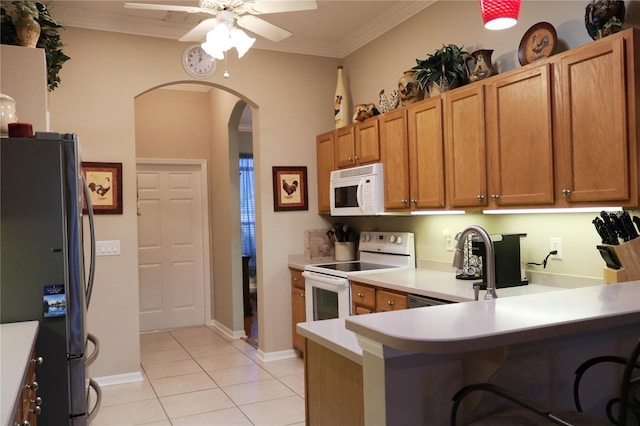 kitchen with kitchen peninsula, white appliances, ceiling fan, crown molding, and light tile patterned floors