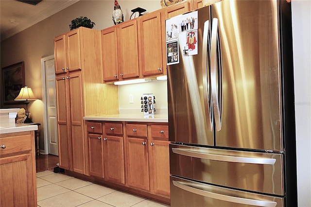 kitchen with stainless steel fridge, light tile patterned floors, and ornamental molding