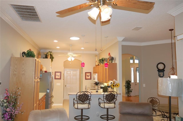 kitchen with kitchen peninsula, stainless steel fridge, a breakfast bar, crown molding, and light tile patterned flooring