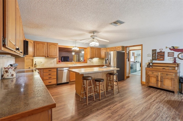 kitchen with a center island, sink, stainless steel appliances, backsplash, and a kitchen bar