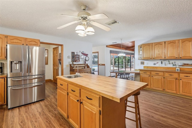 kitchen with sink, stainless steel fridge with ice dispenser, butcher block countertops, light hardwood / wood-style floors, and a kitchen island