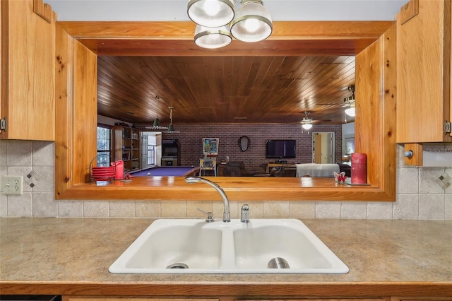 kitchen featuring ceiling fan, sink, and brick wall