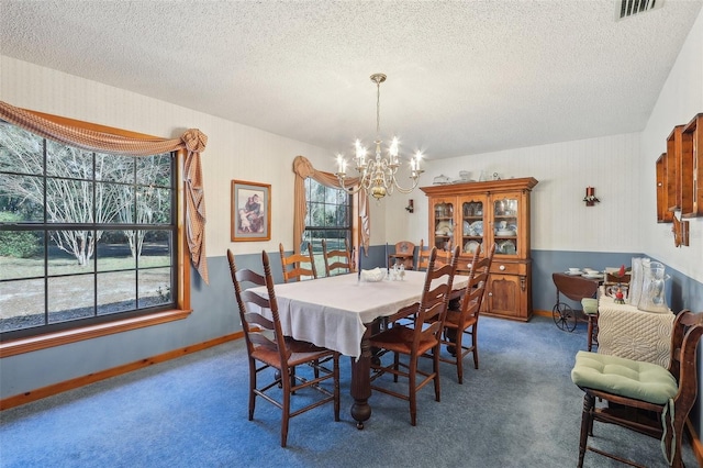 dining room with a textured ceiling, carpet floors, and an inviting chandelier